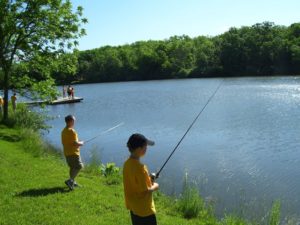 Two boys in yellow shirts fishing on a lake